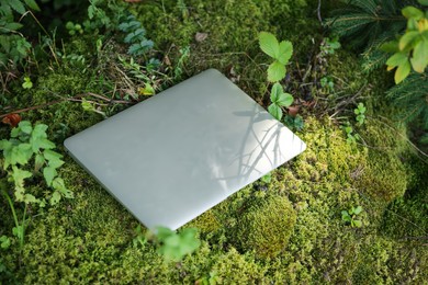 Photo of Laptop on green grass in forest. Distance work