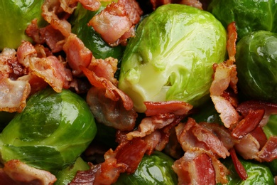 Tasty cooked Brussels sprouts with bacon as background, top view