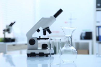 Photo of Laboratory analysis. Different glassware and microscope on white table indoors