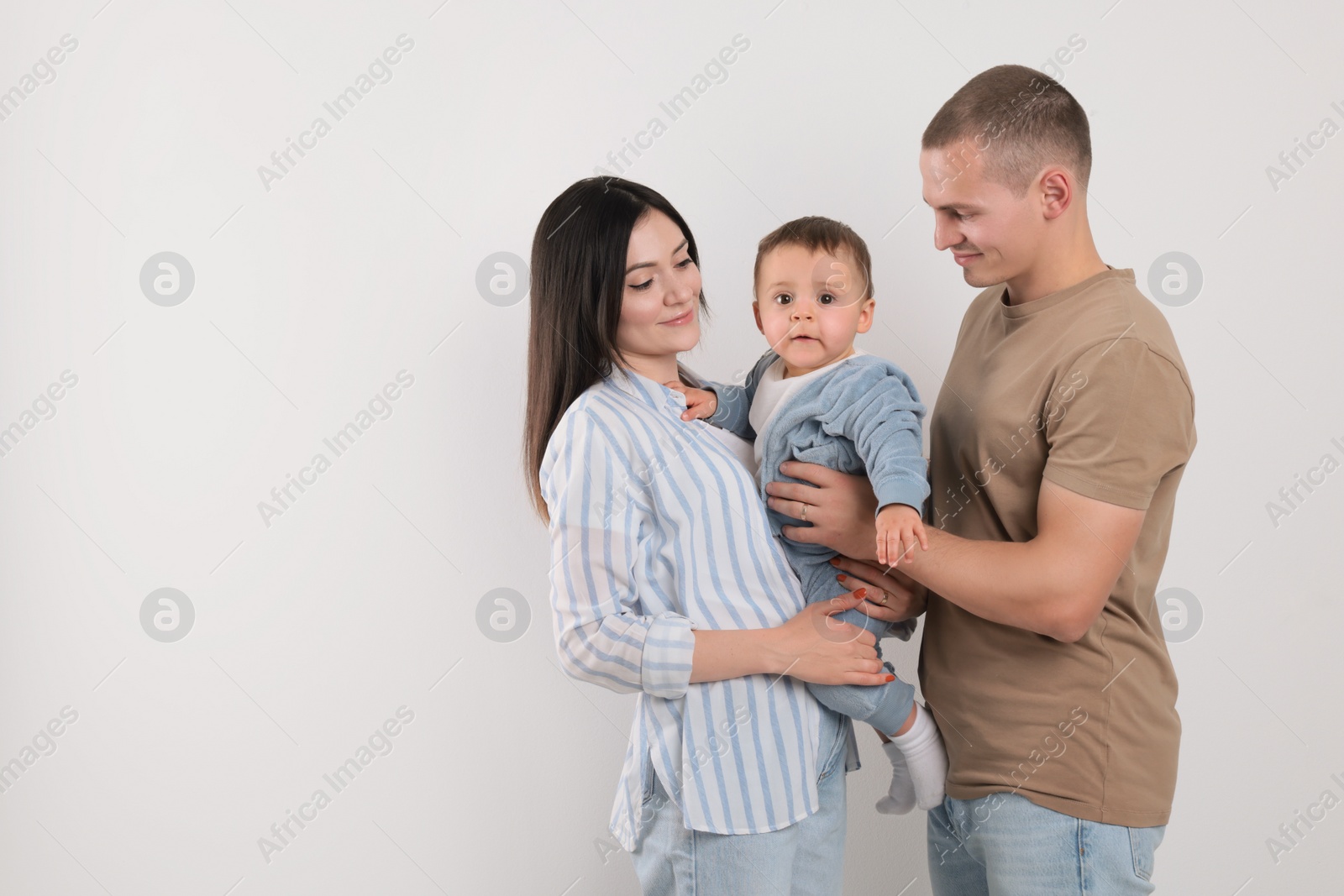 Photo of Portrait of happy family with little child on light background. Space for text