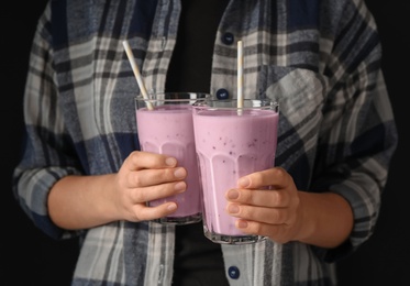 Woman holding fig smoothie on black background, closeup