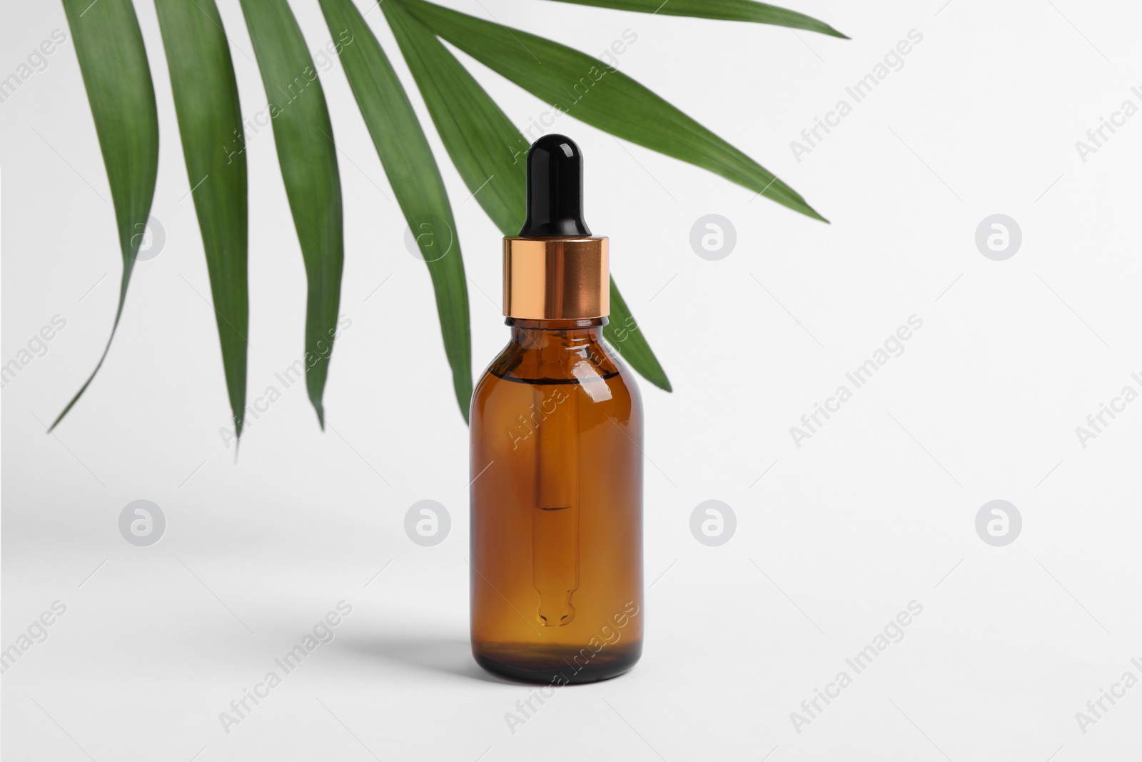 Photo of Bottle with cosmetic oil and green leaf on white background