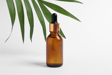 Photo of Bottle with cosmetic oil and green leaf on white background