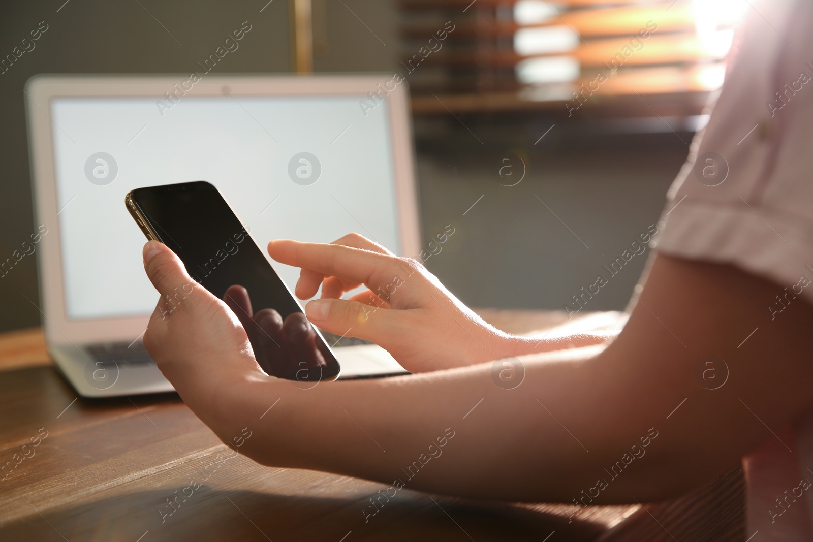 Photo of Woman with modern smartphone at wooden table, closeup