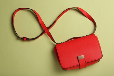 Stylish red women's bag on light green background, top view