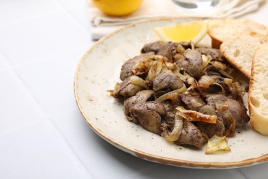 Photo of Tasty fried chicken liver with onion served on white tiled table, closeup. Space for text