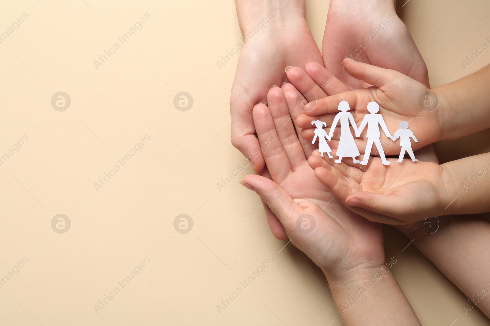 Photo of Parents and child holding paper cutout of family on beige background, top view. Space for text