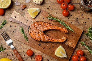 Tasty salmon steak with vegetables and spices served on wooden table, flat lay