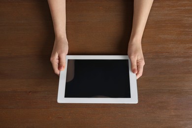 Photo of Woman working with tablet at wooden table, top view