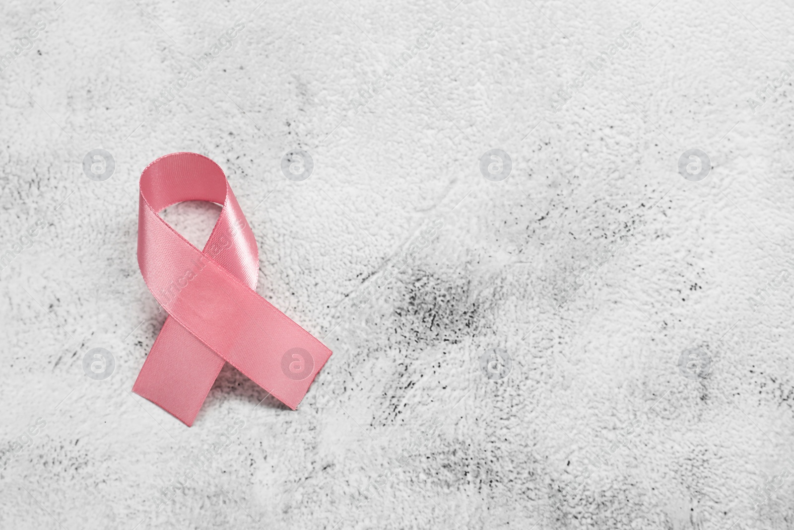 Photo of Pink ribbon on white textured table, top view and space for text. Breast cancer awareness