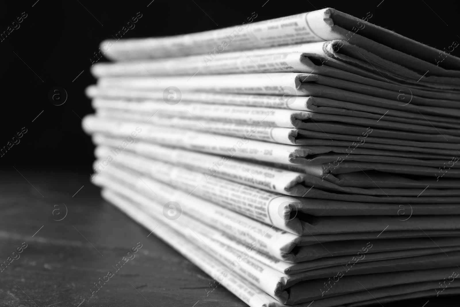 Photo of Stack of newspapers on dark stone table, closeup. Journalist's work