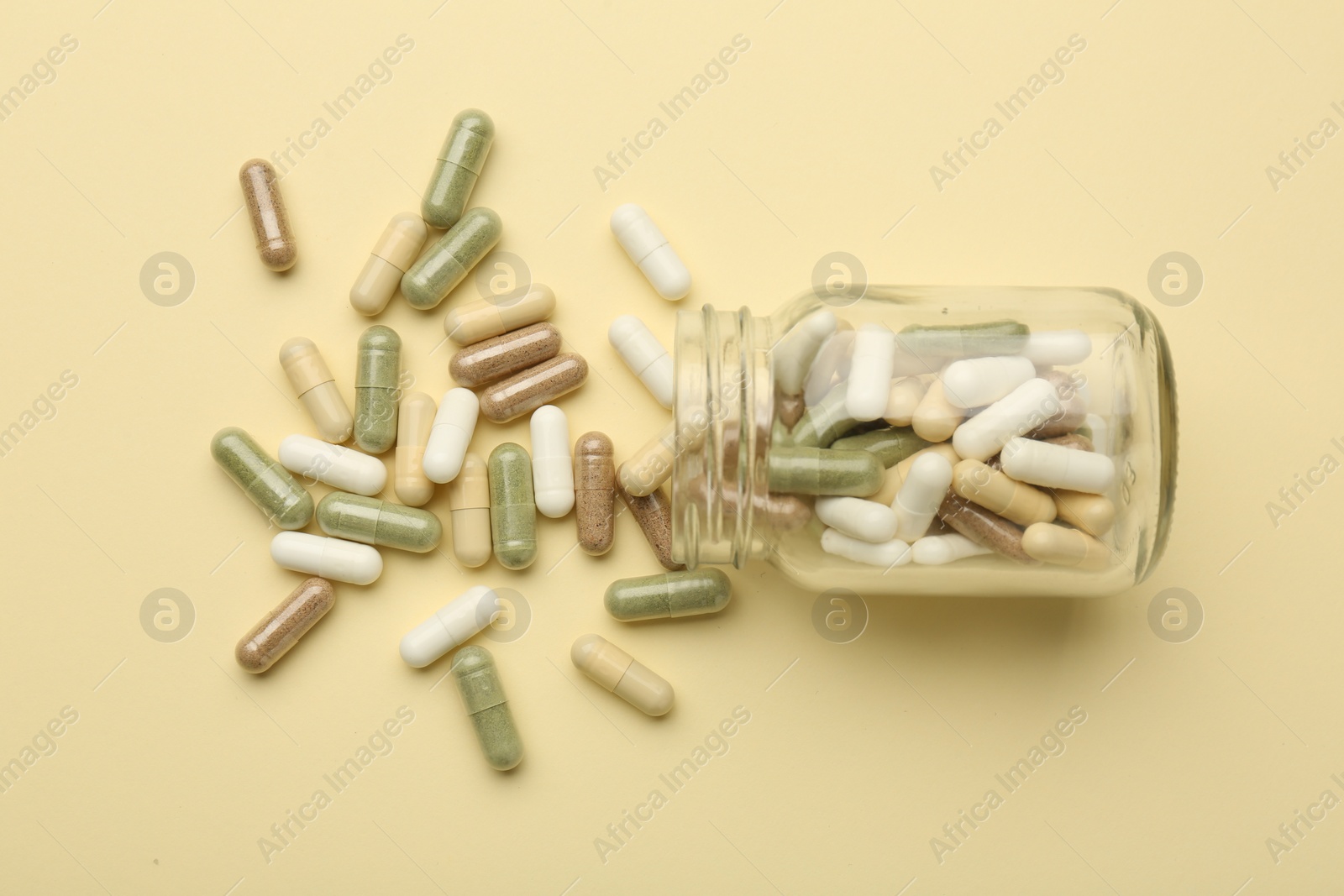 Photo of Vitamin pills and bottle on beige background, top view