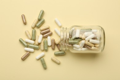 Photo of Vitamin pills and bottle on beige background, top view