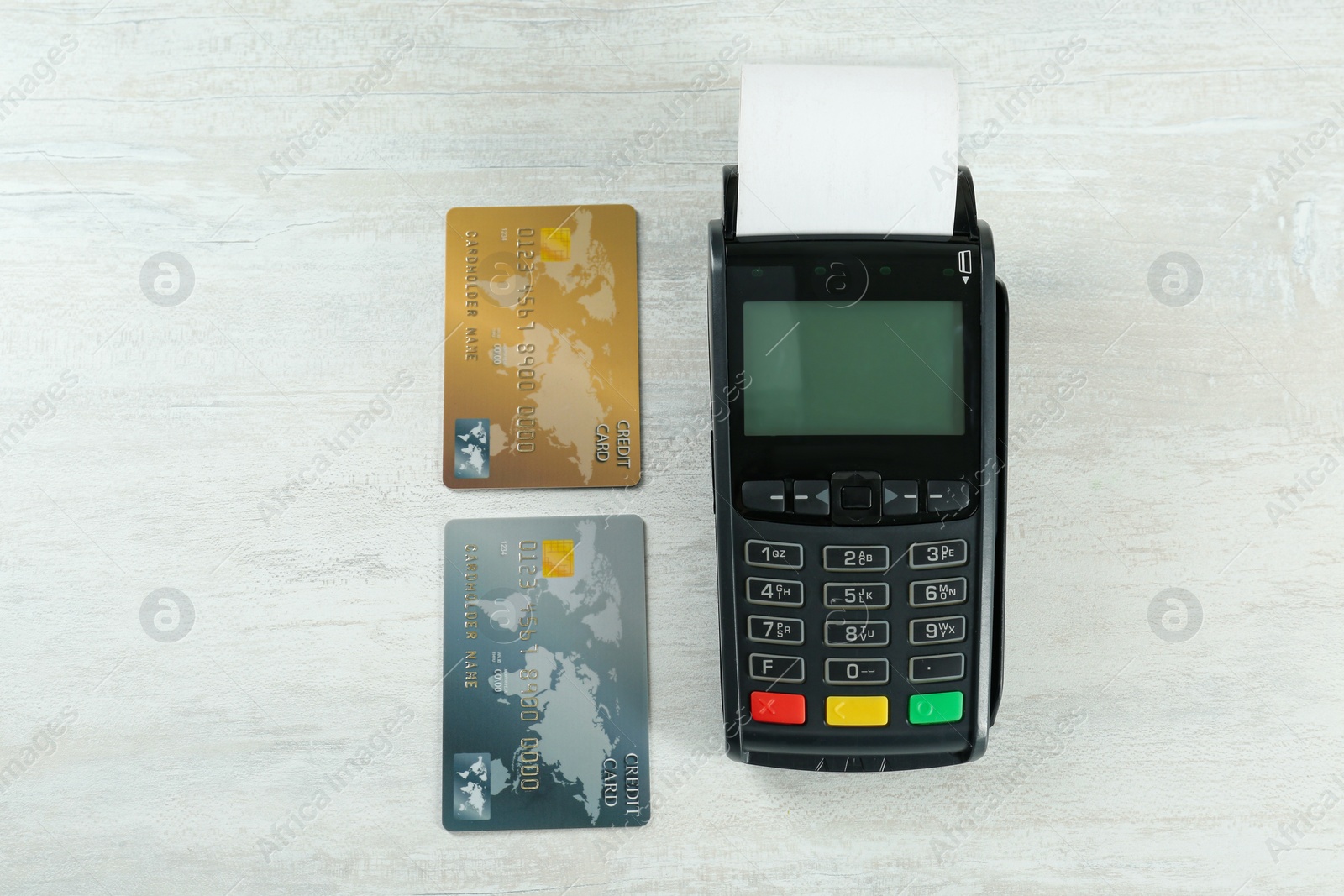 Photo of New modern payment terminal and credit cards on white wooden table, flat lay