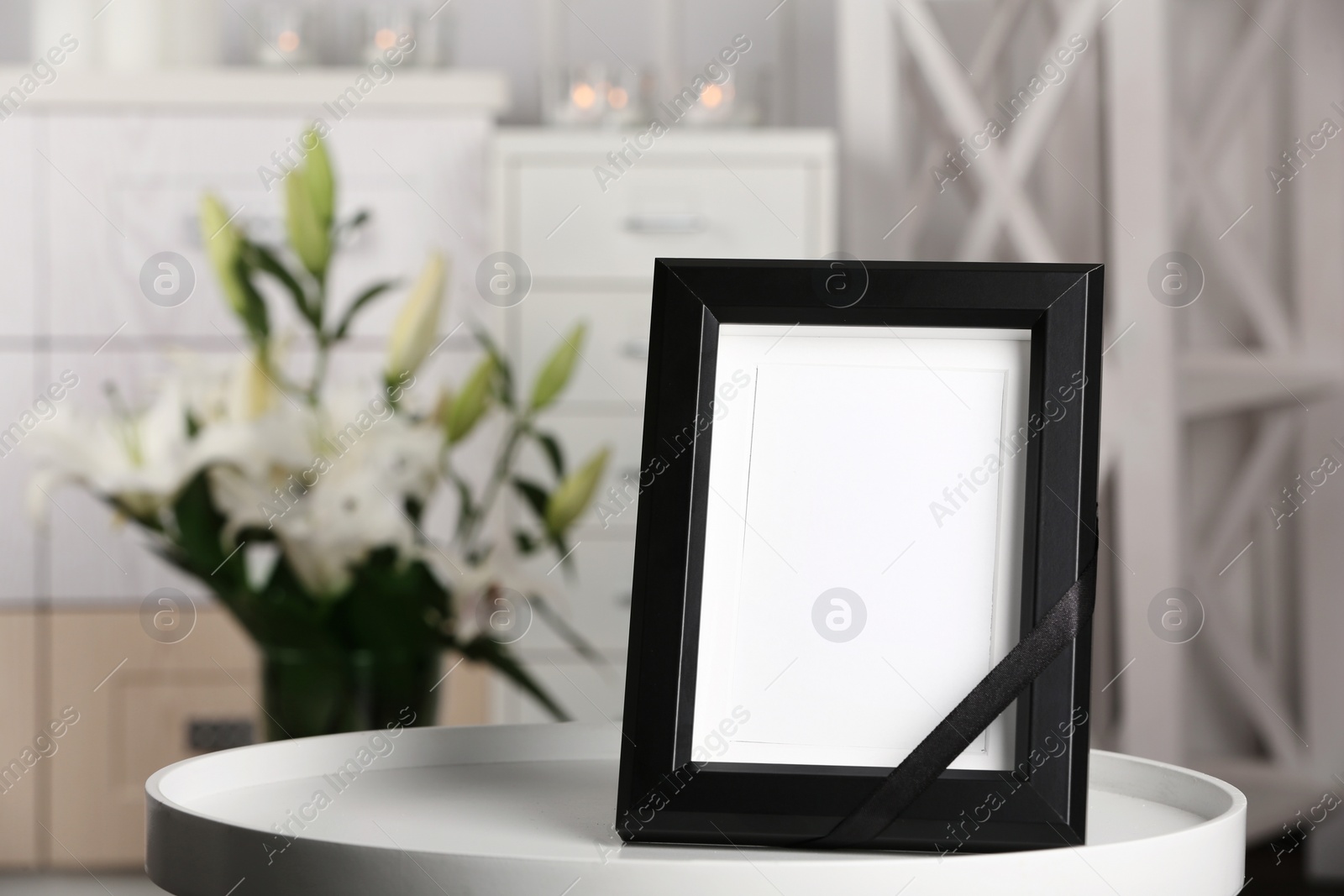 Photo of Funeral photo frame with black ribbon on table, indoors