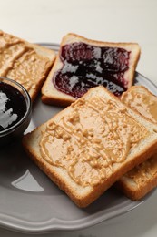 Photo of Delicious toasts with peanut butter and jam on table, closeup