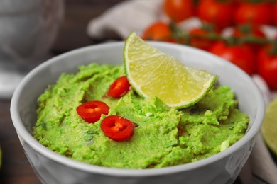 Photo of Delicious guacamole and lime slice in bowl, closeup