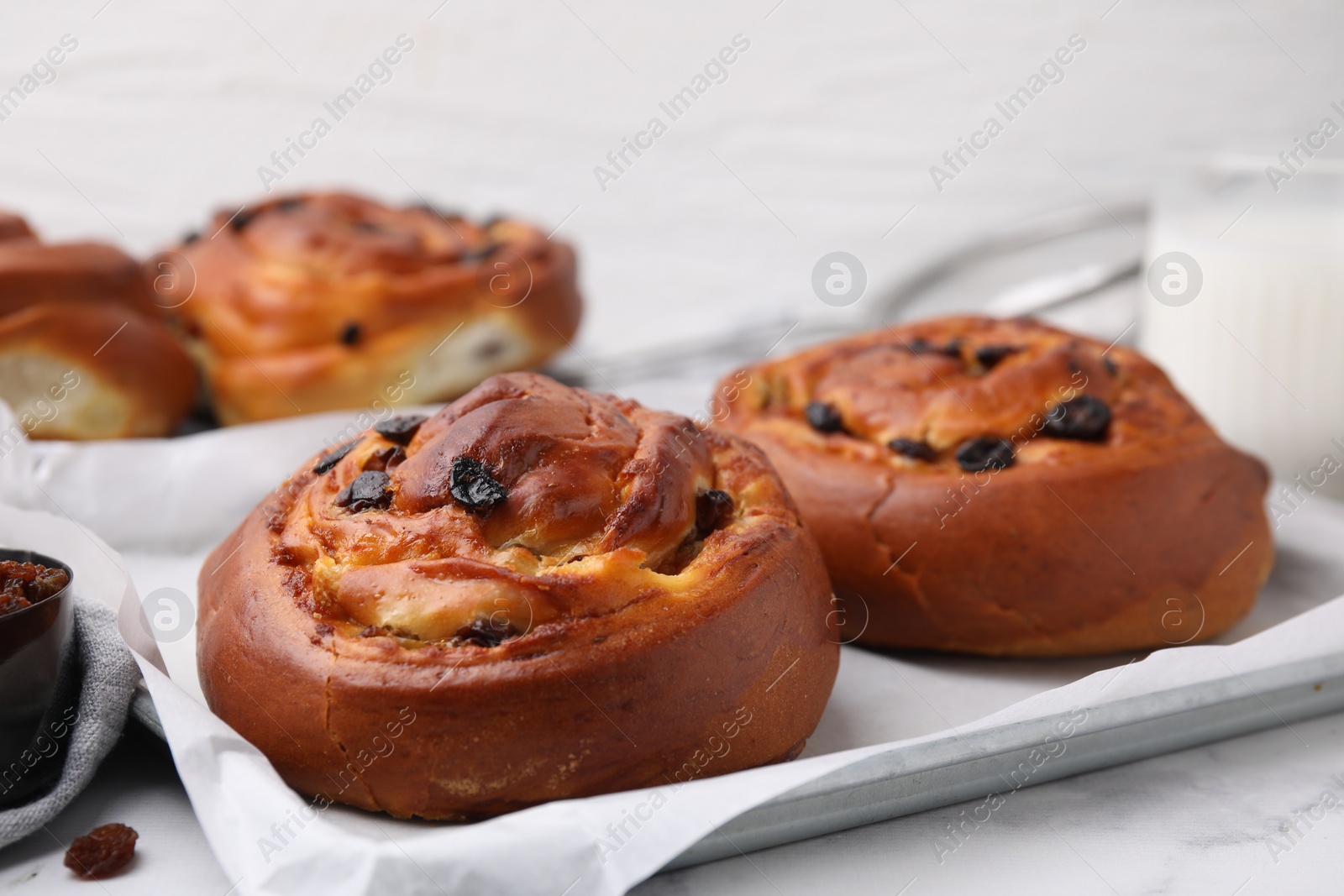 Photo of Delicious rolls with raisins on white table, closeup. Sweet buns