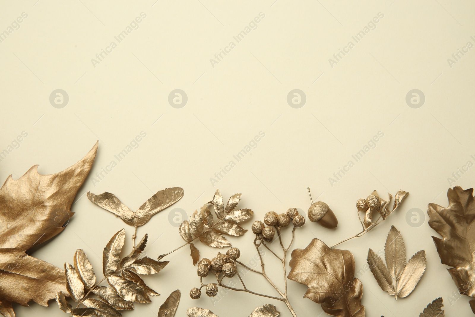 Photo of Beautiful golden leaves, berries and acorn on beige background, flat lay with space for text. Autumn decor