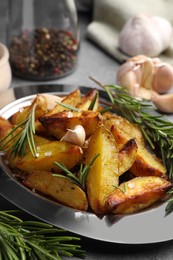 Photo of Plate with tasty baked potato and aromatic rosemary on grey table, closeup