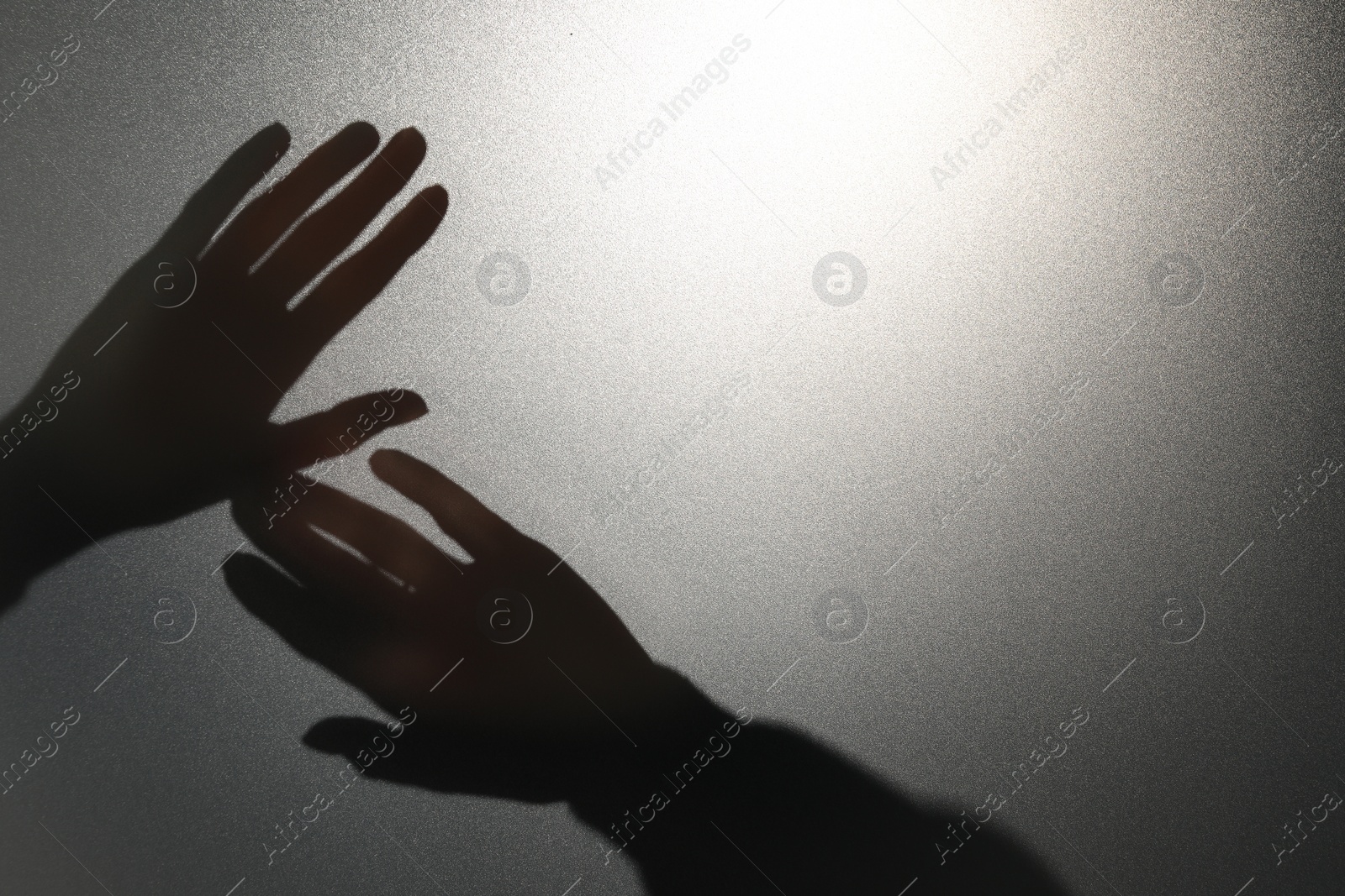 Photo of Silhouette of ghost behind glass against light grey background, closeup. Space for text