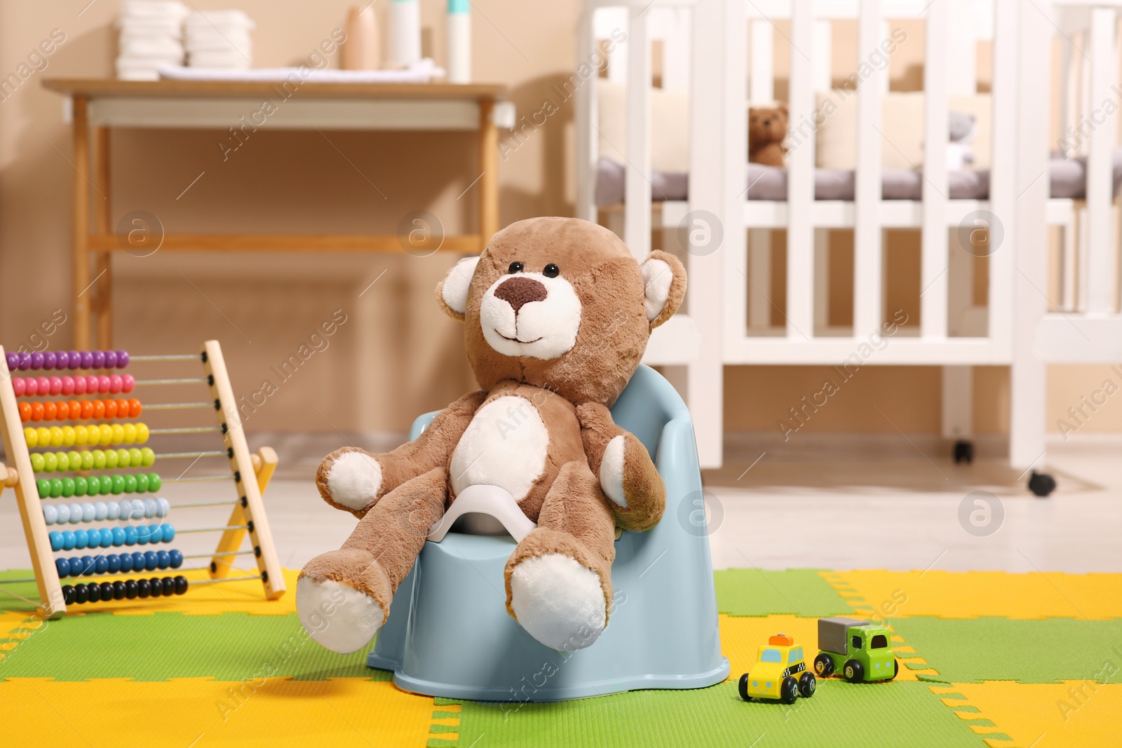 Photo of Cute teddy bear on light blue baby potty in room. Toilet training