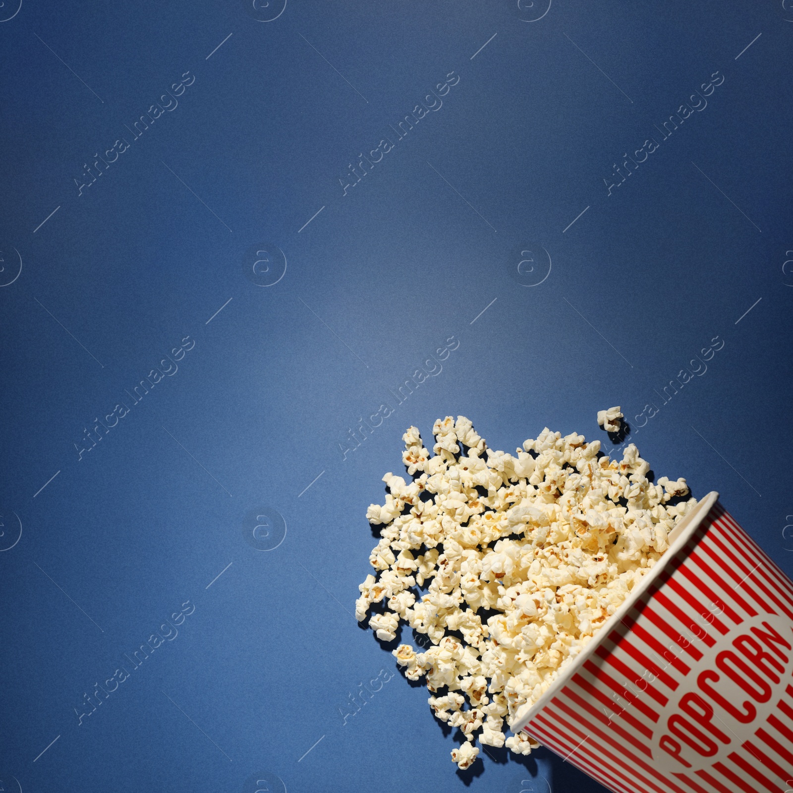 Photo of Delicious popcorn on blue background, top view. Space for text