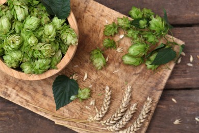Photo of Fresh green hops and ears of wheat on wooden table, flat lay