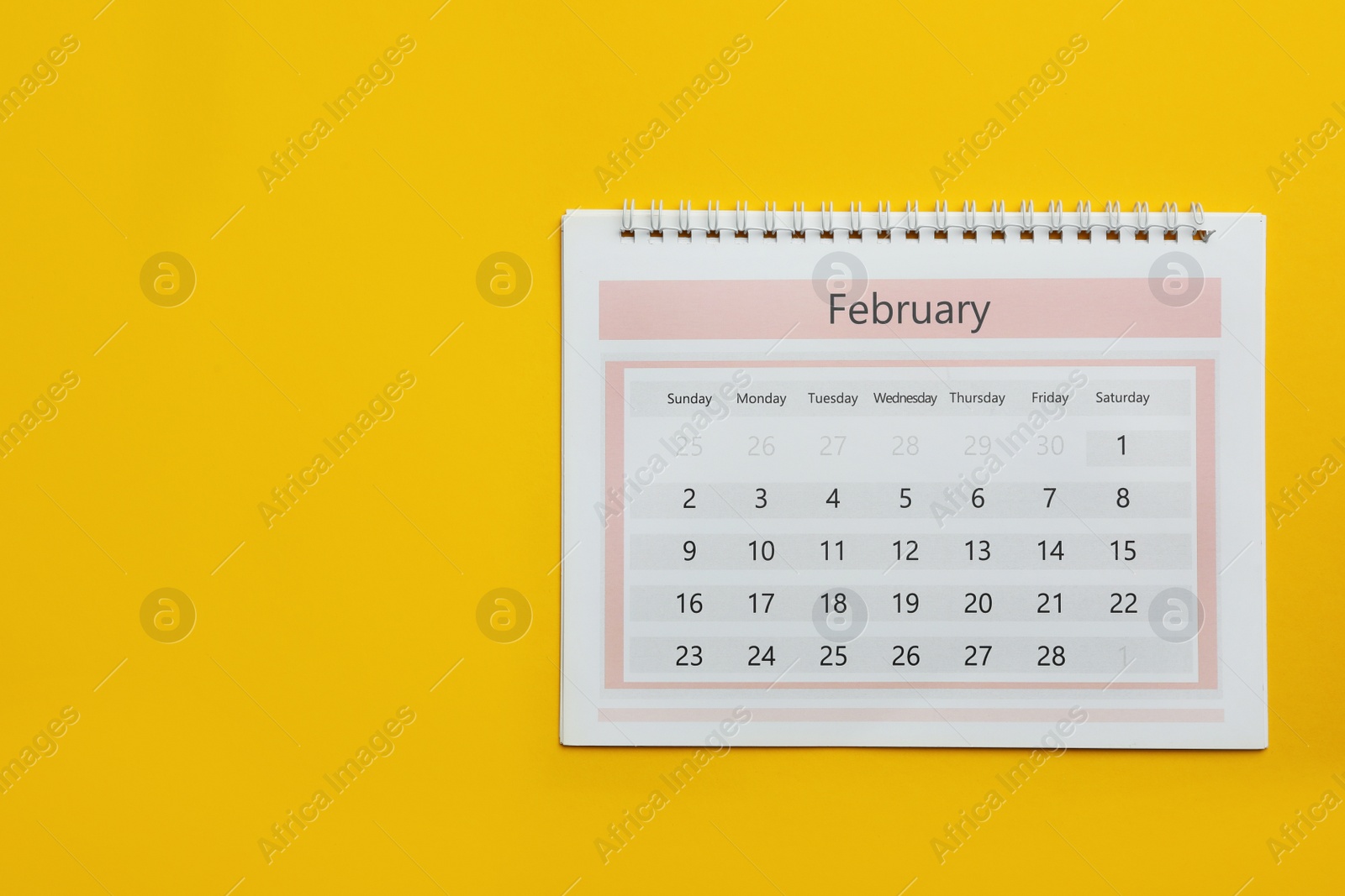 Photo of February calendar on yellow background, top view. Space for text