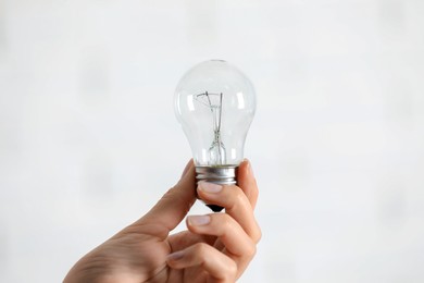 Photo of Woman holding light bulb on white background, closeup