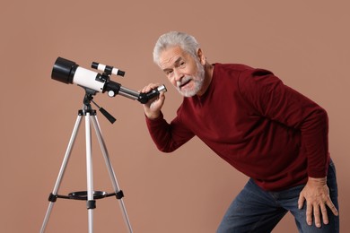 Senior astronomer with telescope on brown background