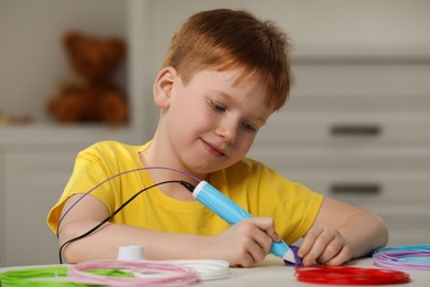 Photo of Boy drawing with stylish 3D pen at white table