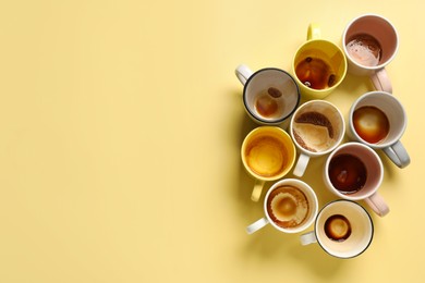 Photo of Many dirty cups after drinking coffee on yellow table, flat lay. Space for text