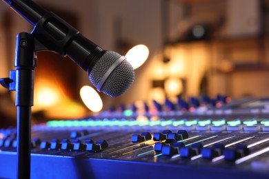 Photo of Microphone near professional mixing console in radio studio, closeup