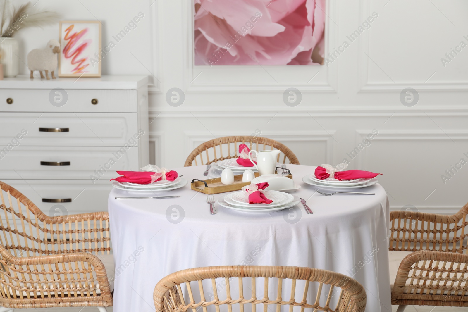 Photo of Color accent table setting. Plates, cutlery and pink napkins in dining room