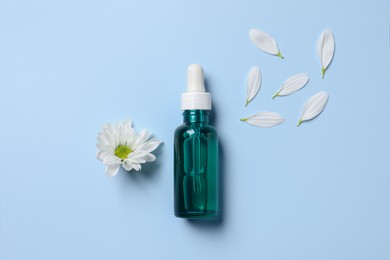 Photo of Bottle of cosmetic serum, beautiful flower and petals on light blue background, flat lay