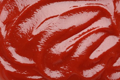 Photo of Tasty ketchup as background, top view. Tomato sauce