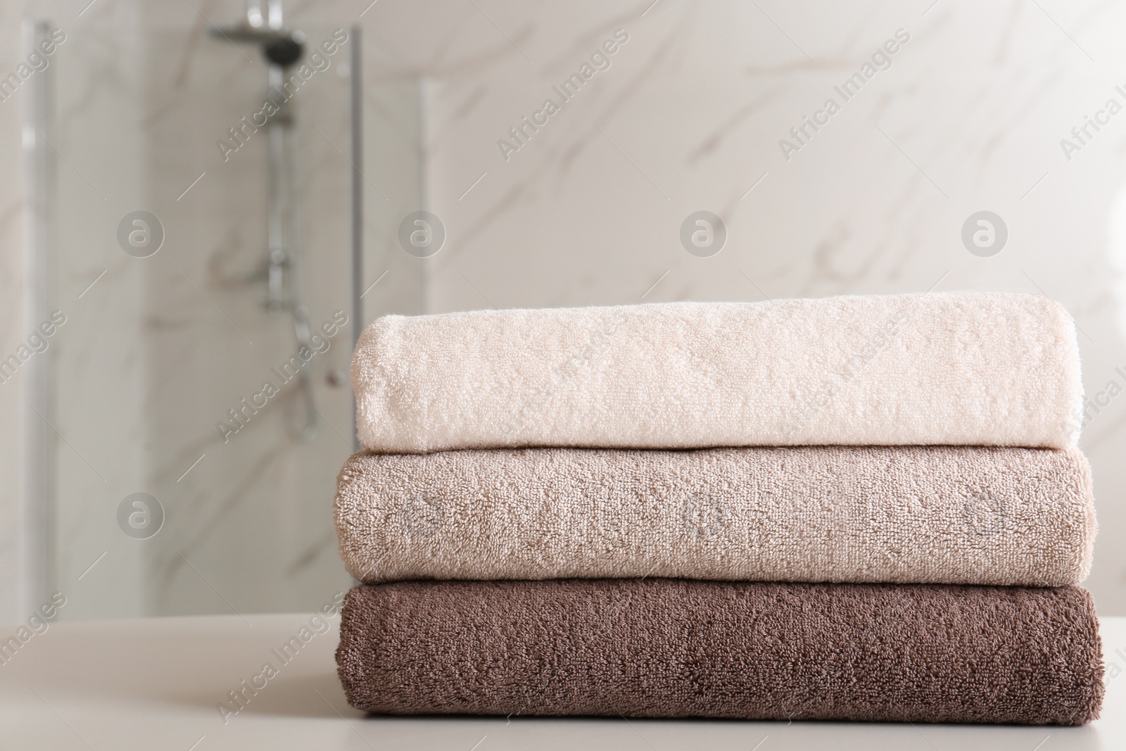 Photo of Stack of clean towels on table in bathroom. Space for text