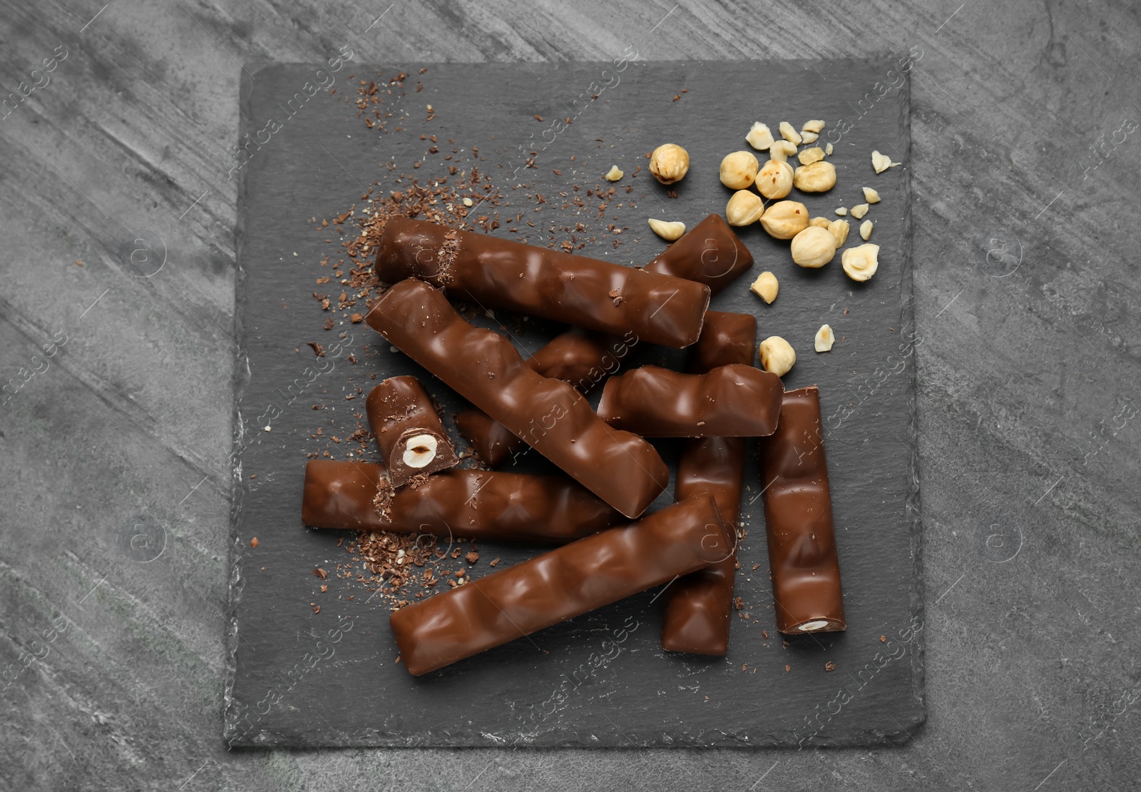 Photo of Tasty chocolate bars with nuts on black table, top view