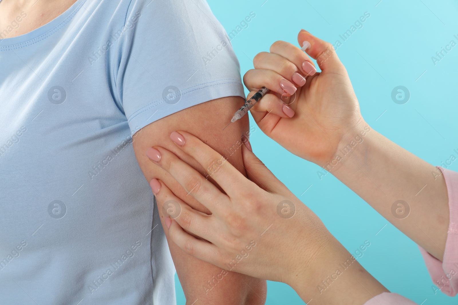 Photo of Diabetes. Woman getting insulin injection on light blue background, closeup