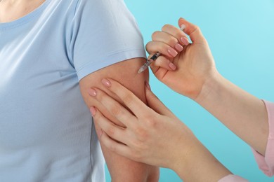 Diabetes. Woman getting insulin injection on light blue background, closeup