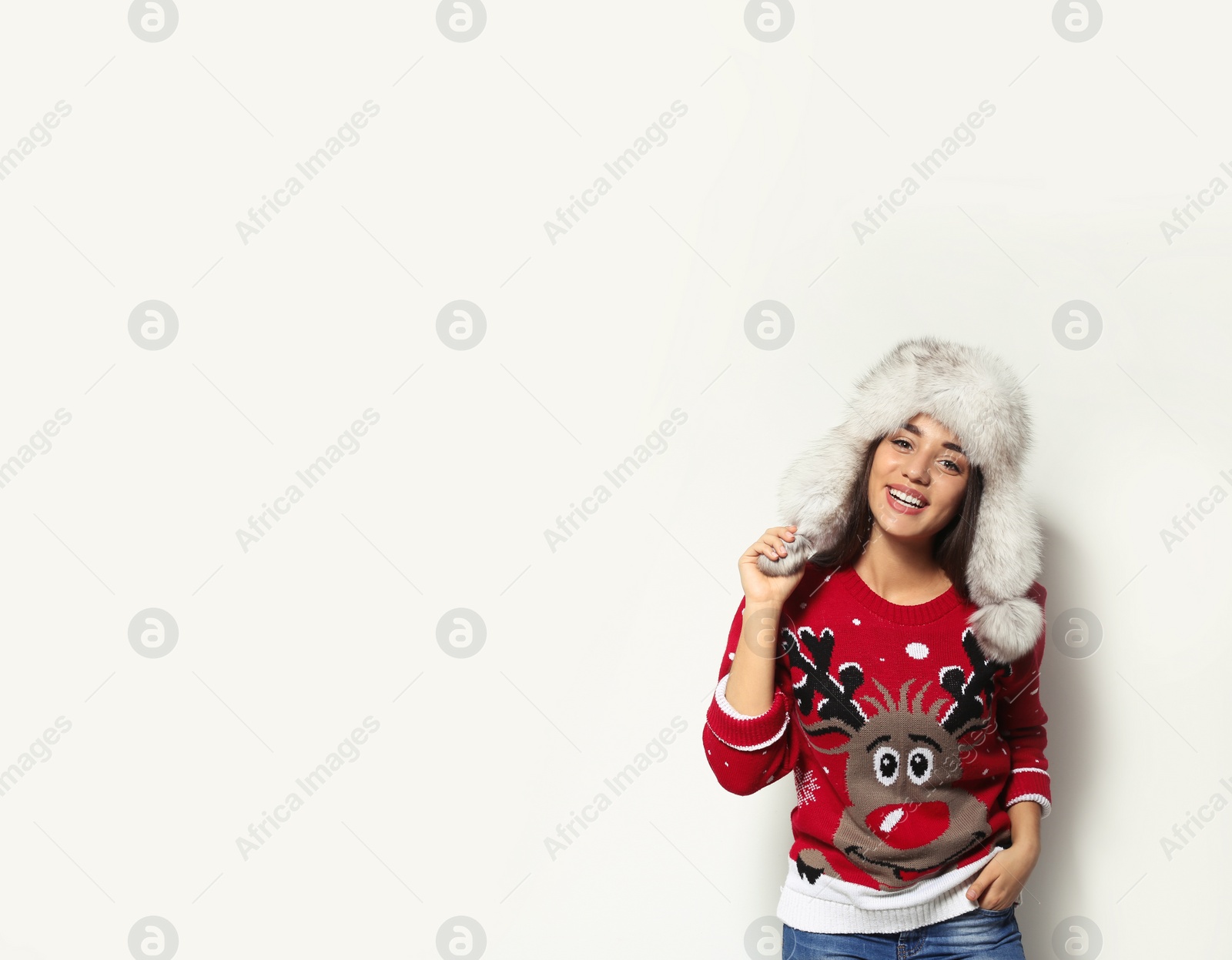 Photo of Young woman in Christmas sweater and hat on white background. Space for text