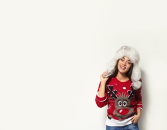 Photo of Young woman in Christmas sweater and hat on white background. Space for text