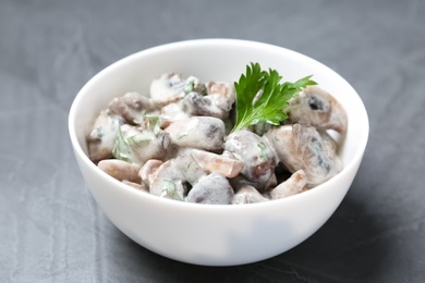 Photo of Bowl of fried mushrooms with sauce on grey table