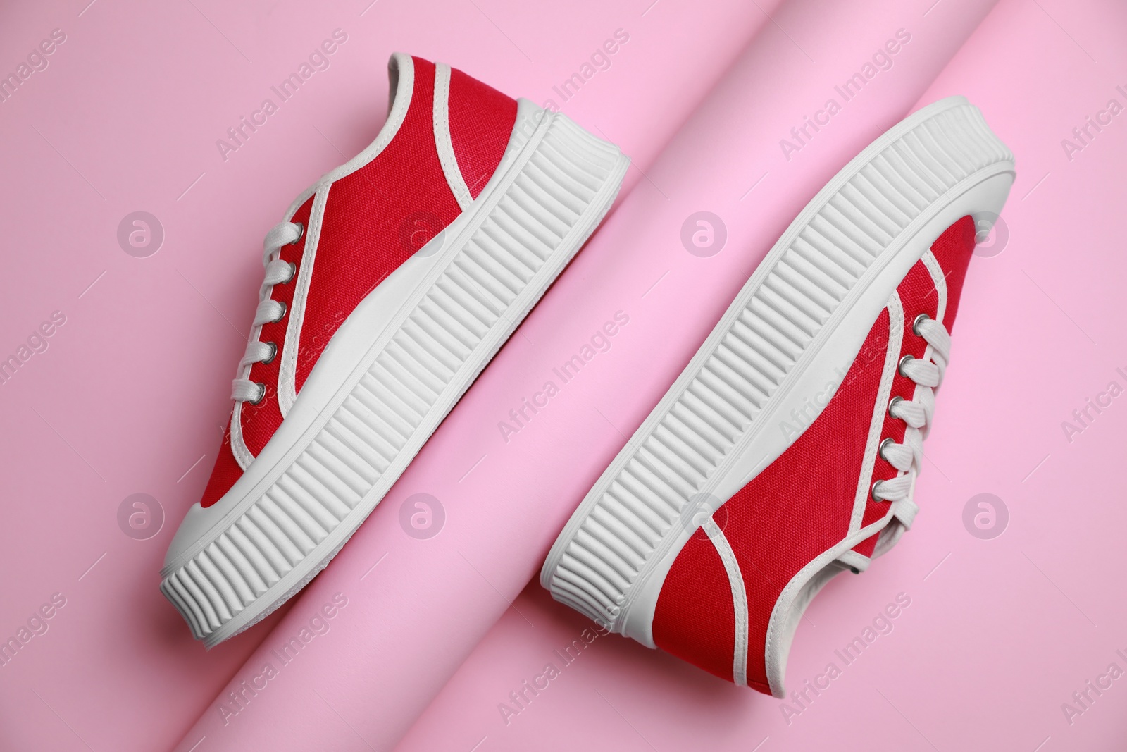 Photo of Stylish presentation of red classic old school sneakers on pink background, flat lay