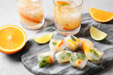 Photo of Ice cubes with orange and mint on light grey table