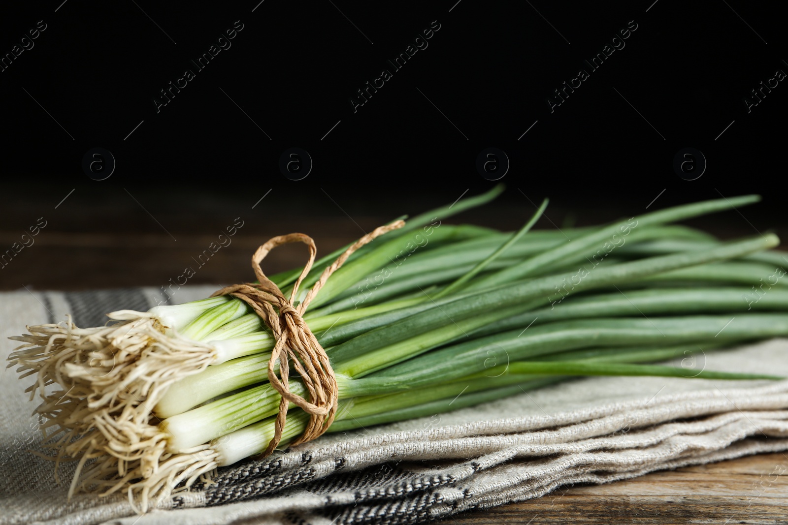 Photo of Fresh green spring onions on wooden table, closeup