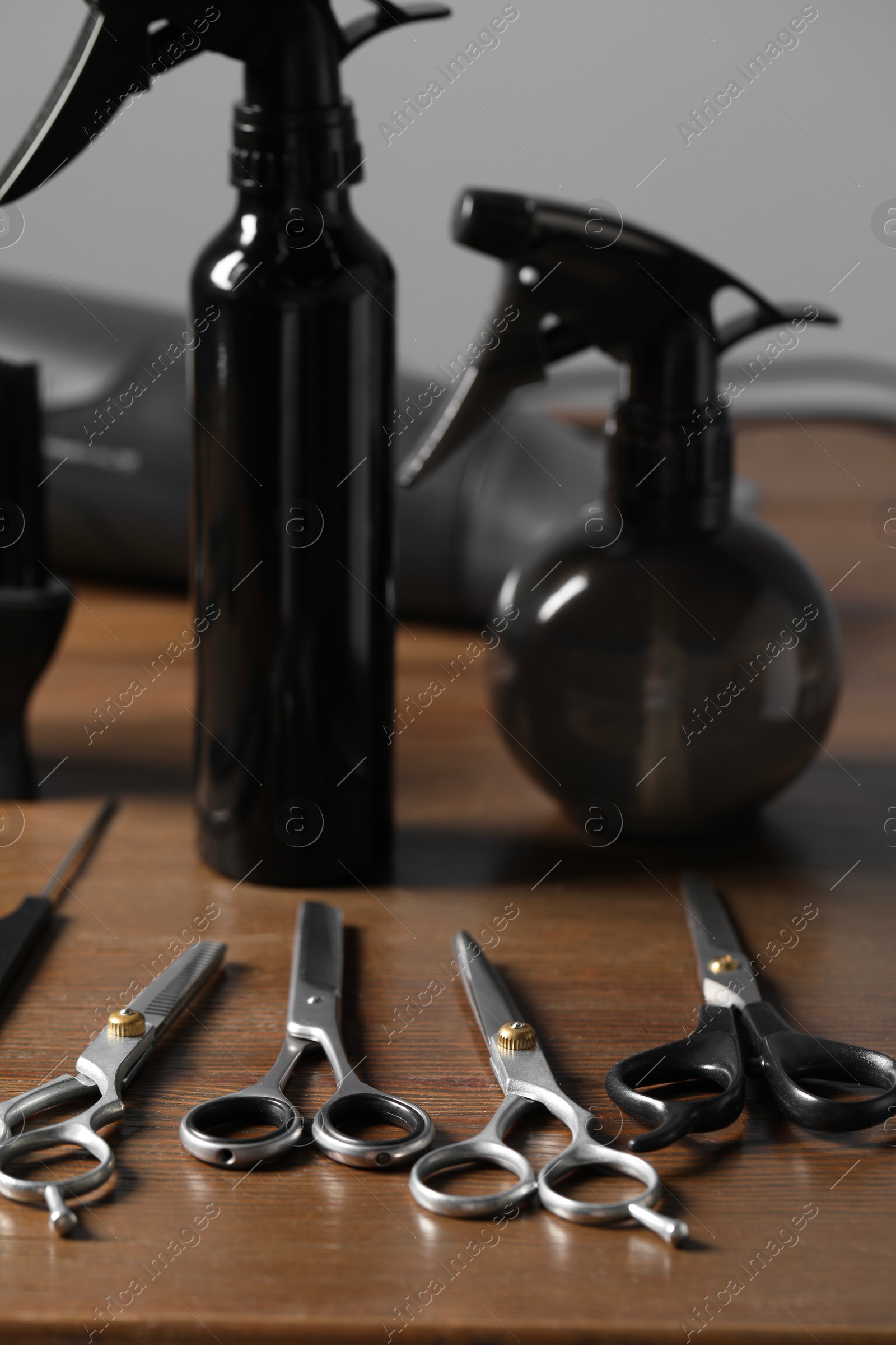 Photo of Hairdresser tools. Different scissors and combs on wooden table in salon, closeup