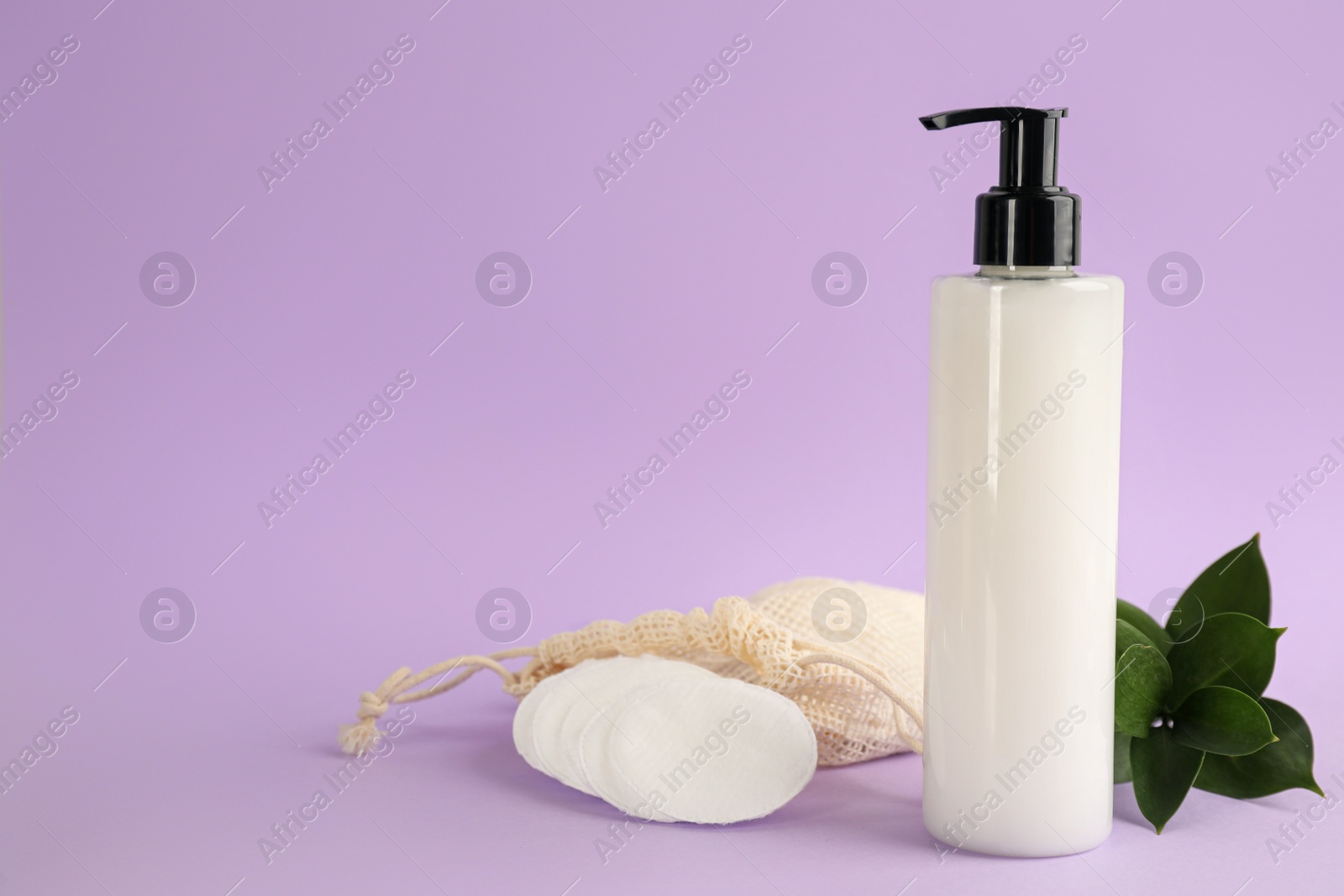 Photo of Cotton pads, leaves, sack and makeup removal product on violet background. Space for text