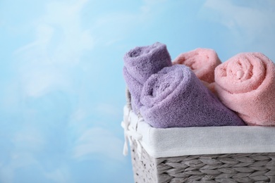 Basket with soft bath towels on color background. Space for text